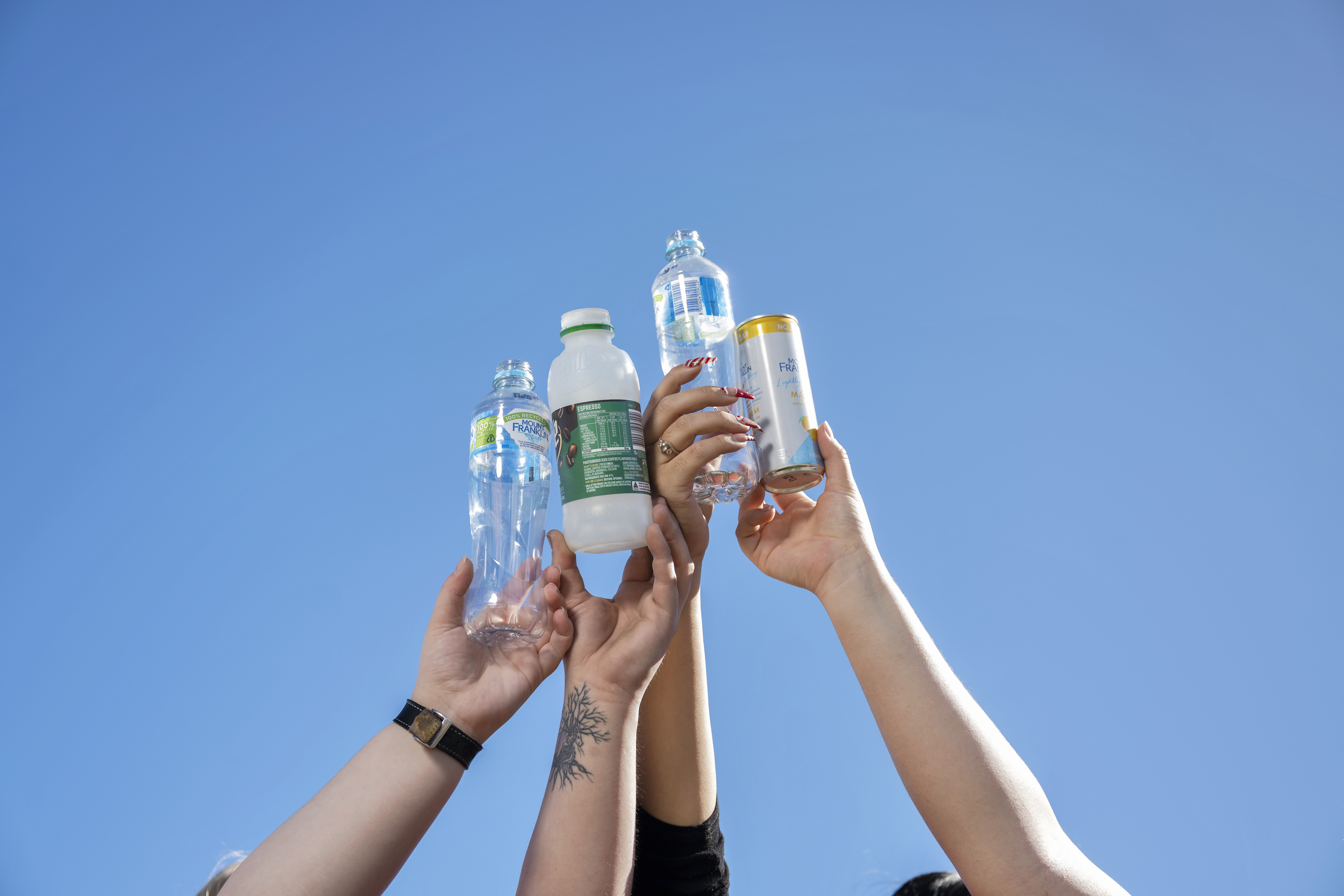 group of people holding up empty drink bottles in the sky
