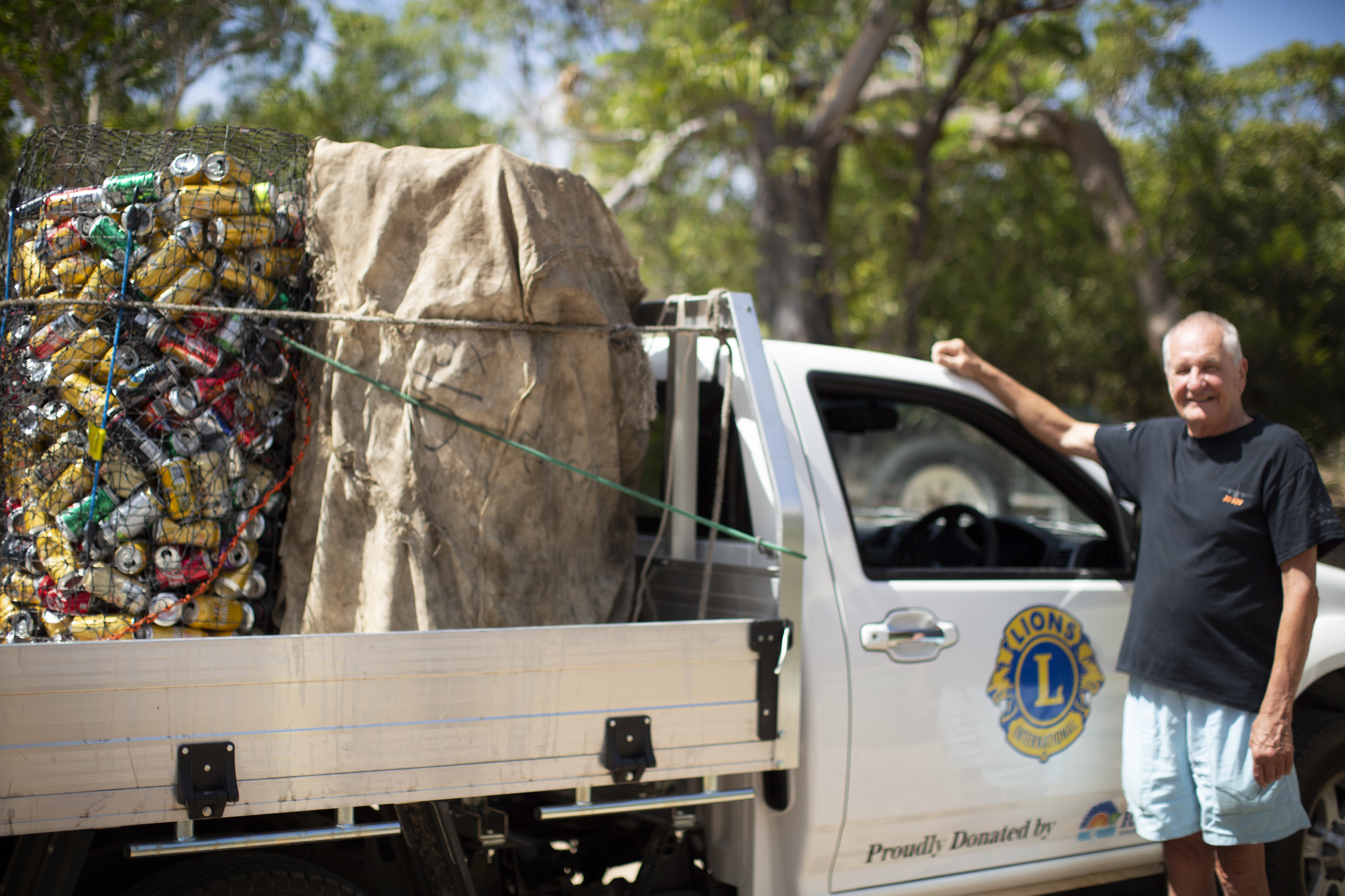 Smiling man alongside ute full of recycling