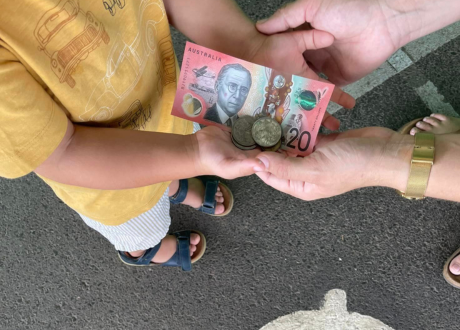 child holding $20 bank note and coins
