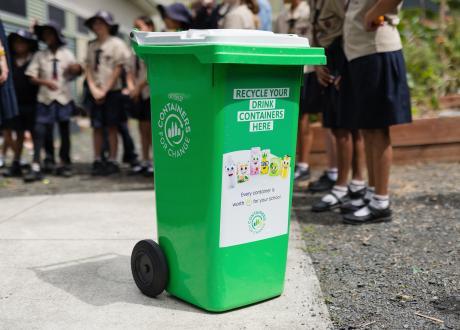 Green container bin in front of children