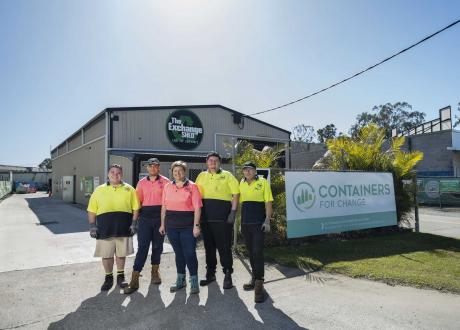 Team photo of people stand in front of a large shed
