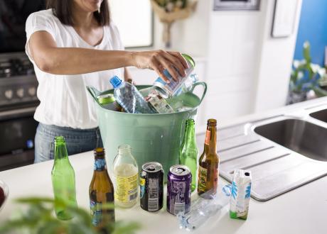 Lady sorting out empty plastic and glass bottles and cans on her kitchen bench to get her 10 cent refund from Containers for Change