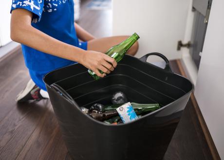 Young person sorts drink containers under the sink