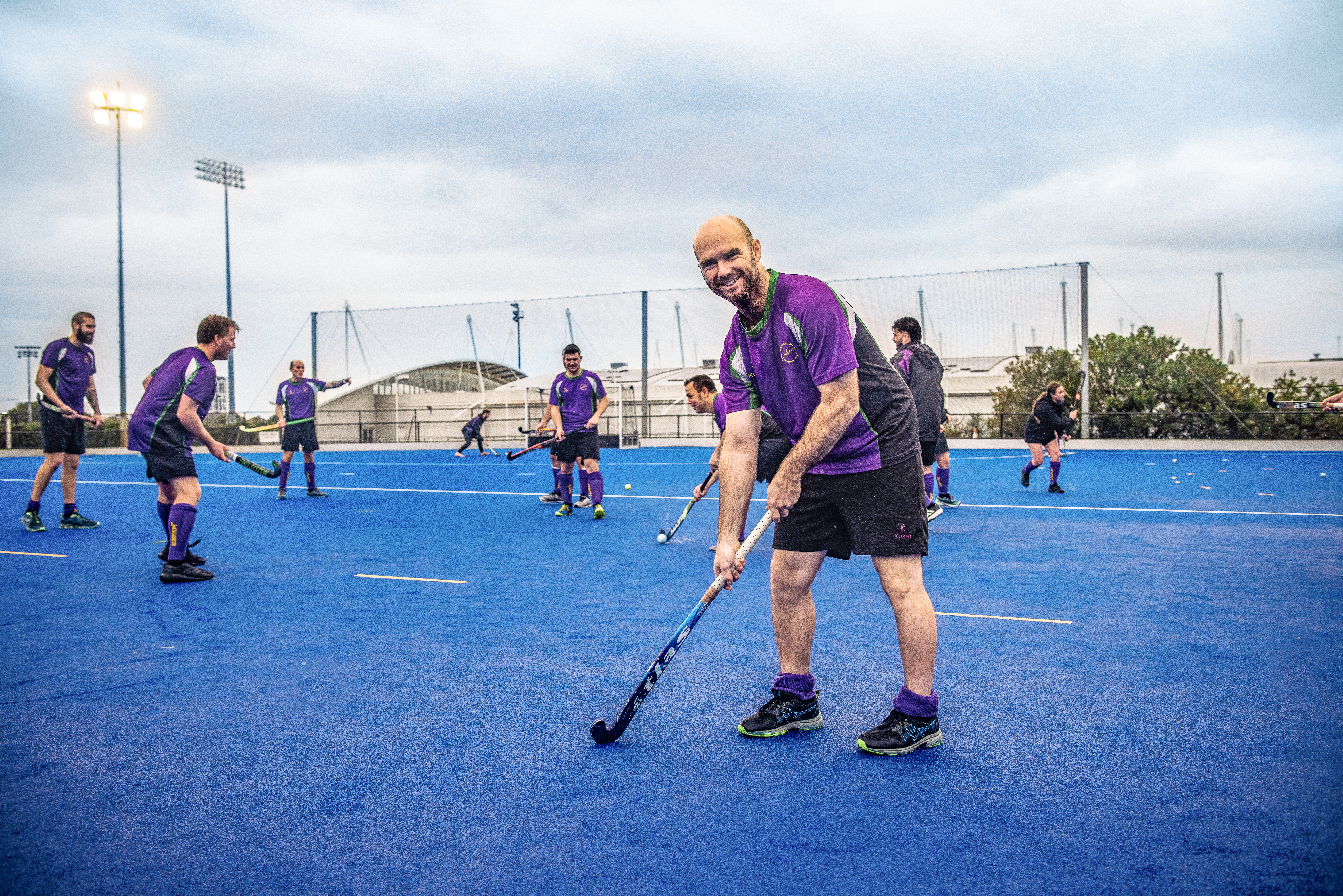 man posing with a hockey stick on a hockey field