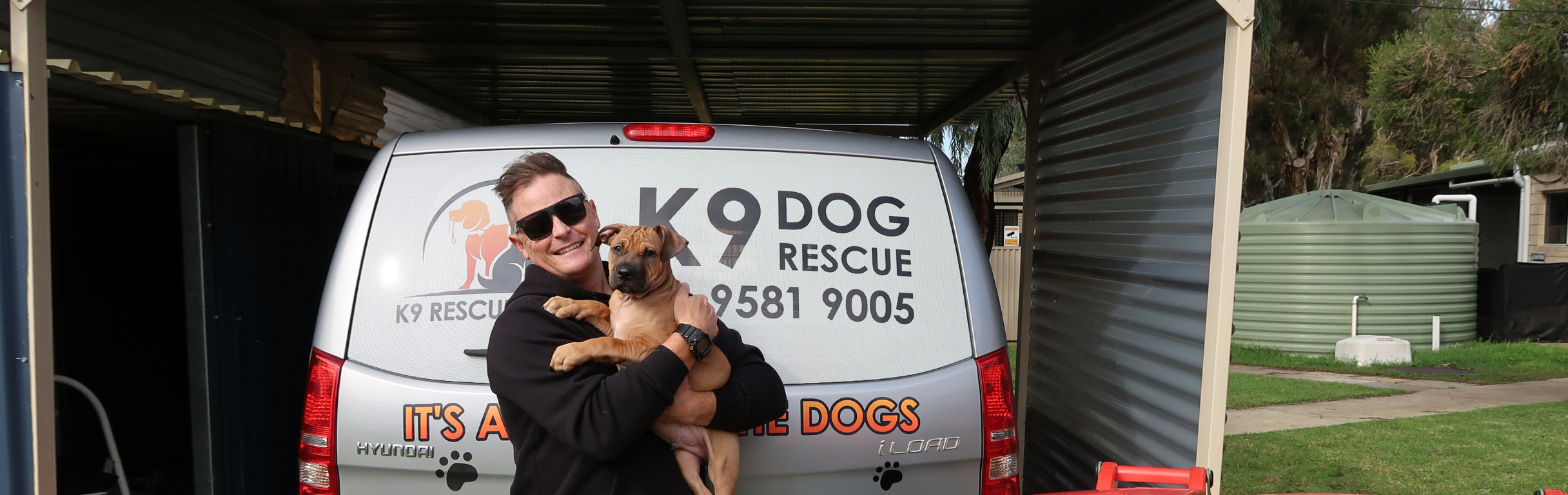a man from k9 dog rescue holding a puppy