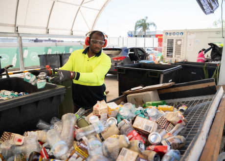 A refund point operator is counting a large amount of drink containers into a big black bin.